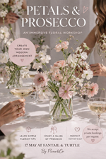 Advertisement for a floral workshop with flowers and Prosecco on a table.