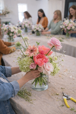 Floral workshop with participants arranging flowers at a table.