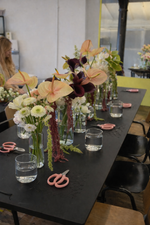 Floral arrangement setup on a table with flowers, scissors, and water glasses.