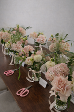 Bouquets of flowers on a table with scissors, against a plain background

