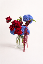 Bouquet of red and blue flowers in a clear vase on a white background